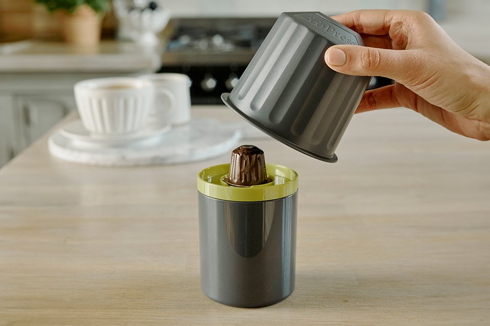 A person using a Dualit EcoPress™ capsule recycler to recycle coffee capsules.